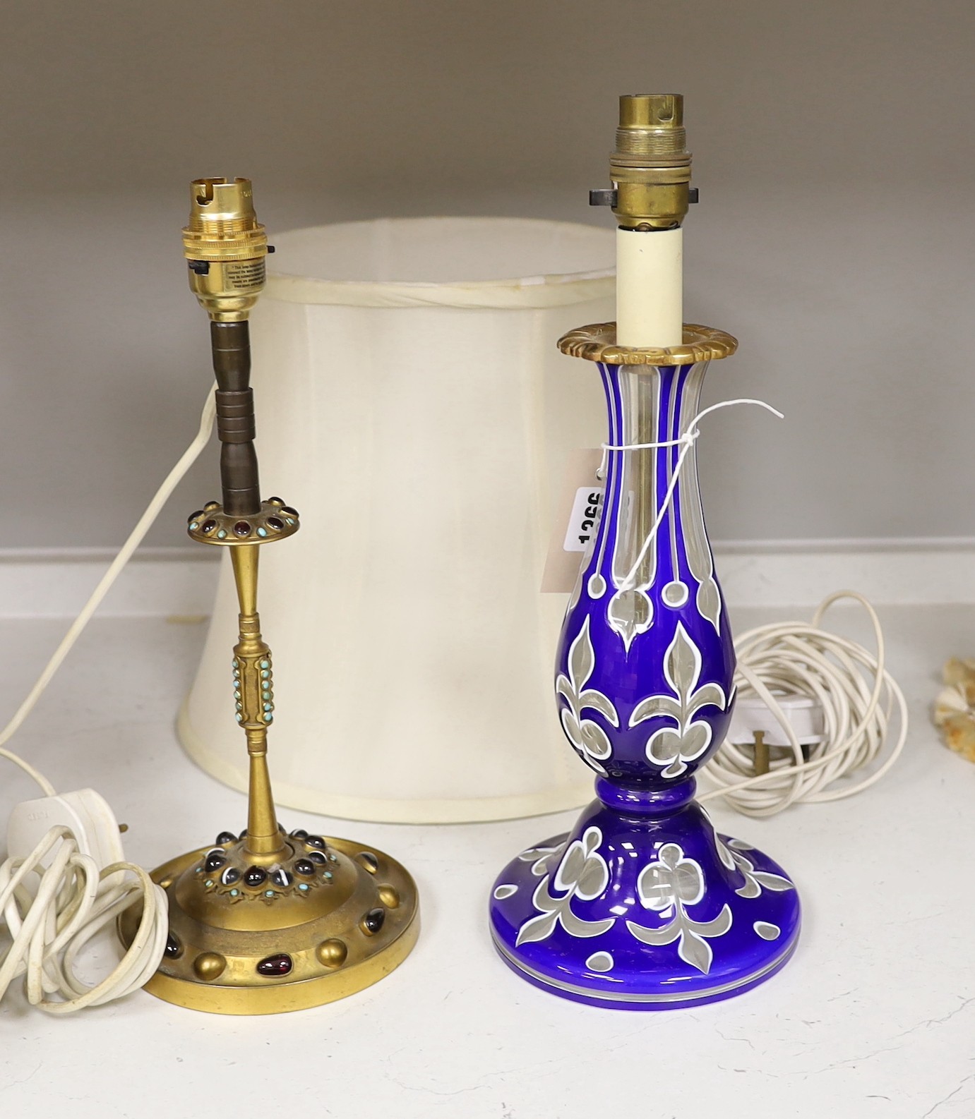 A Bohemian blue and white overlaid glass pedestal converted to a table lamp, together with a gilt brass table lamp, inset with hardstone cabochons, one with a lampshade, tallest 36cm